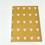 Schriftje A5 `Happy` Oker met roze hartjes