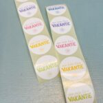 Sticker rond 35mm `Een hele fijne vakantie met zonnetje` op witte basis met gekleurde letters ( mix van 10 stuks )